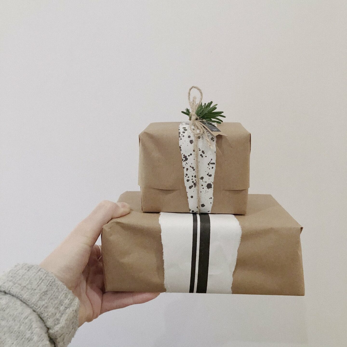 Hand holding a stack of sustainably wrapped brown paper presents